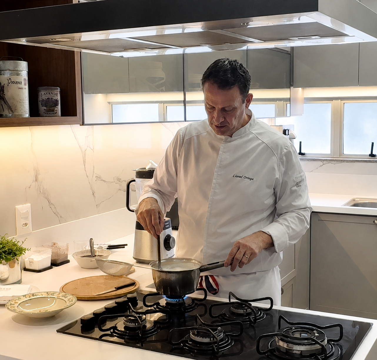 Fotografia real do Chef Lionel Ortega preparando molhos na cozinha.